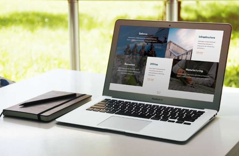 A laptop displaying the SAGE website, showcasing the different industries it serves, including Defence, Infrastructure, and Manufacturing.